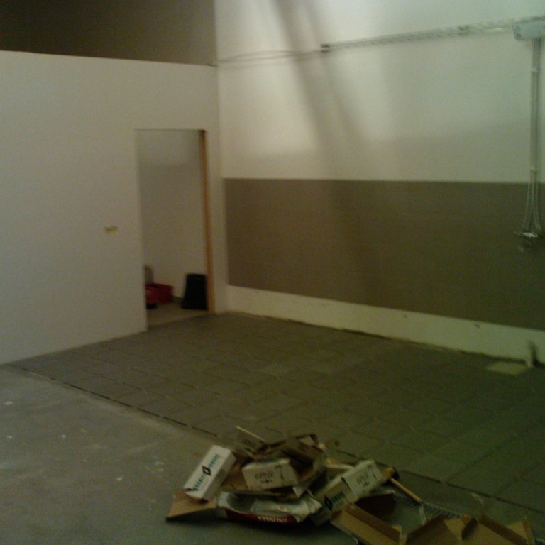 Unnið að flísalögn, sér í hurð inn á skrifstofu- salernis og kaffiaðstöðu