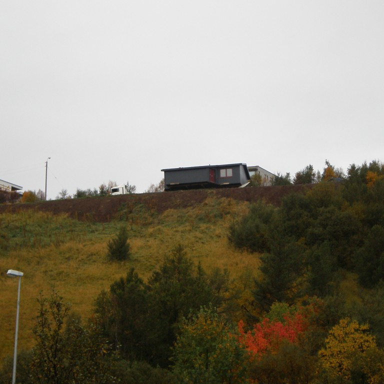Húsið ber við himinn á leið niður brekkuna